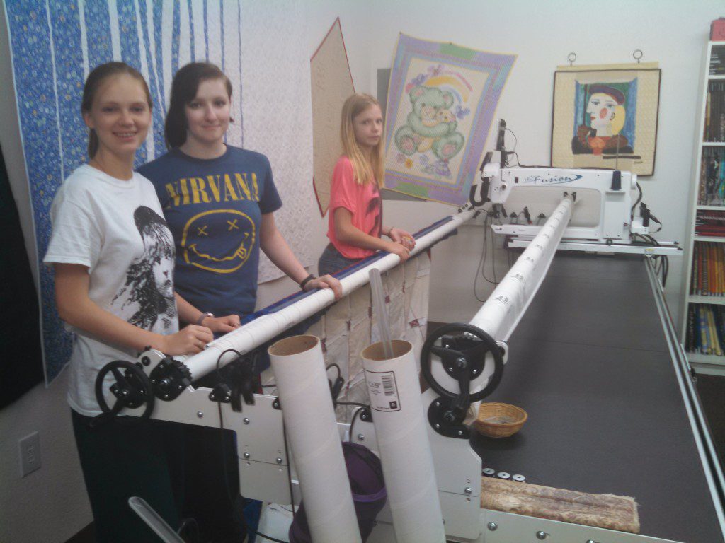 Kayleen Allen's Granddaughters, Emily, Kaelyn and Anna volunteer on the longarm.