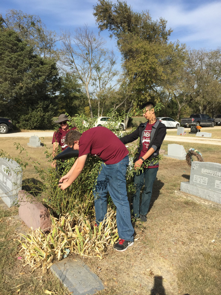 Youth clear brush from tombstones